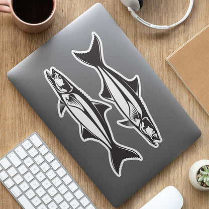 Cool fish decals on a laptop alongside a keyboard and coffee mug.