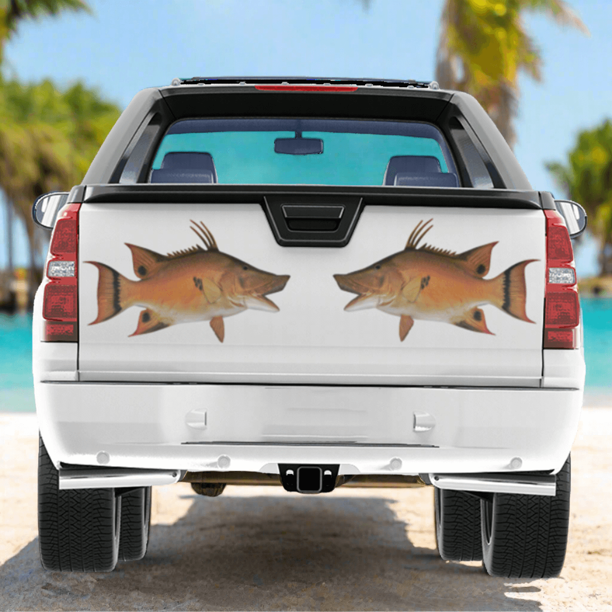 A large Hogfish decal on a pickup truck parked at a beautiful ocean beach.