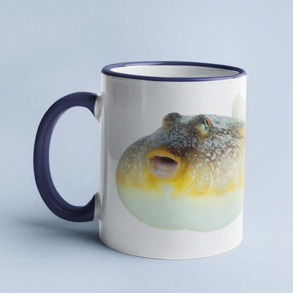 Ceramic mug with a pufferfish design on a light blue background.