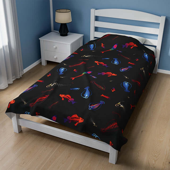 Plush blanket with glowing skeleton fish design on bed in cozy room