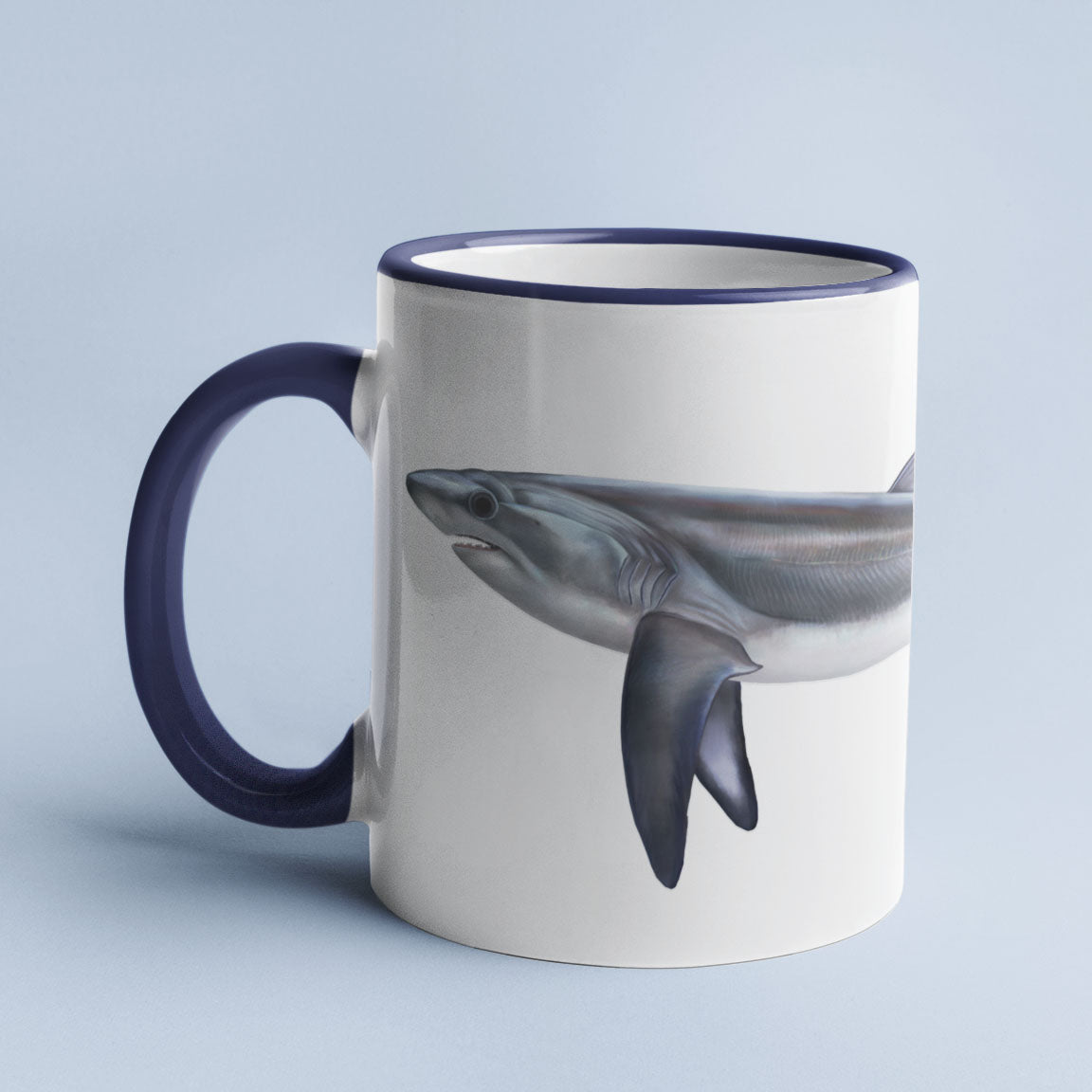 Thresher Shark accent mug with dark blue handle on light blue background.