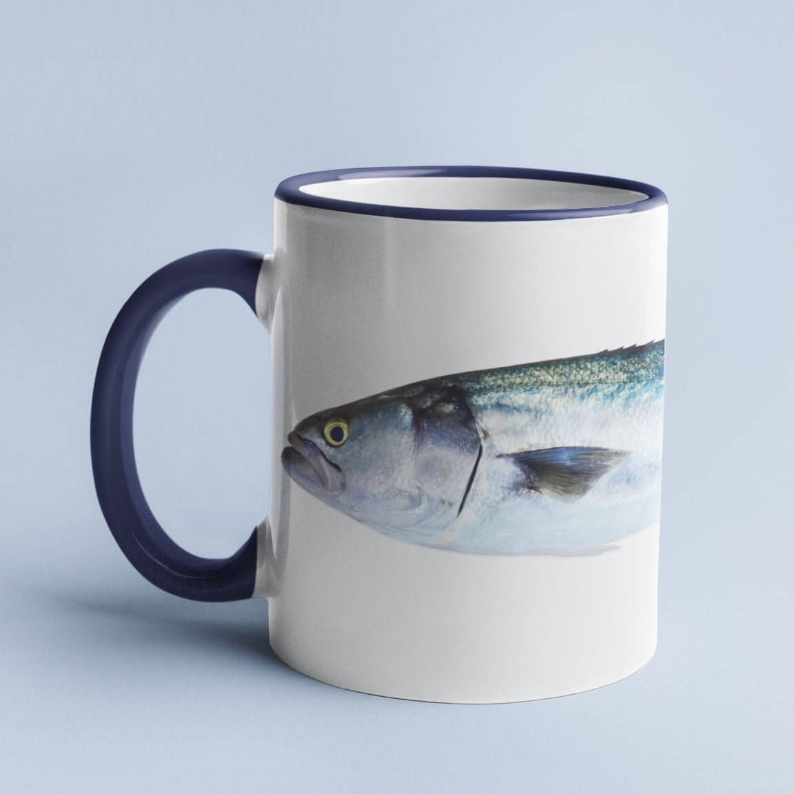 White ceramic mug with a blue handle featuring a realistic fish design against a light blue background.